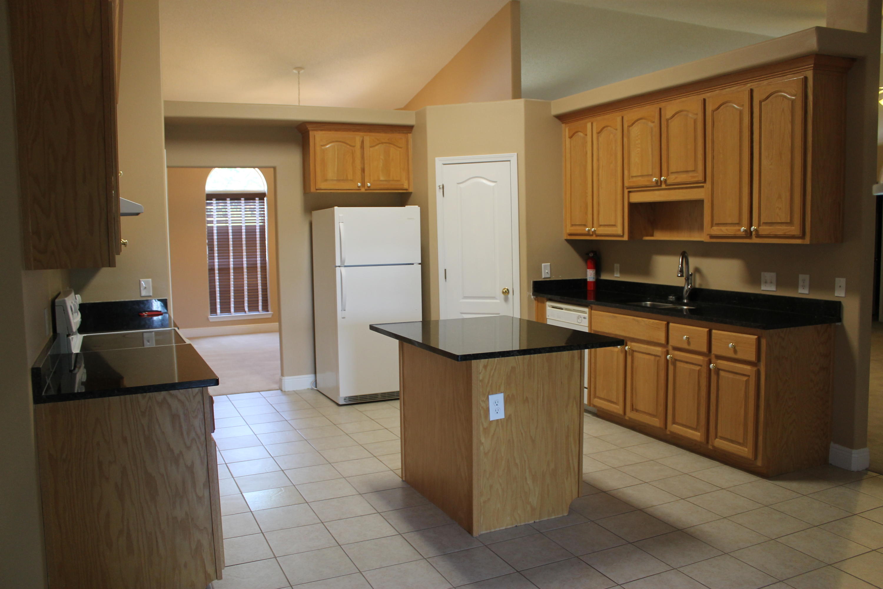 213 Foxchase Way Crestview, FL 32536 - Photo 8 of 34 a kitchen with granite countertop a refrigerator a sink and wooden cabinets