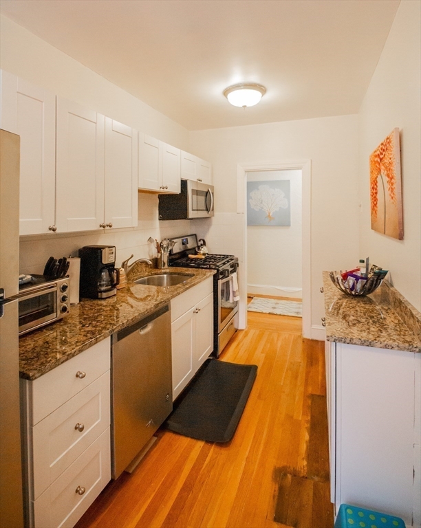 90 Kilsyth Road, Unit 37 Boston, MA 02135 - Photo 4 of 5 a kitchen with stainless steel appliances granite countertop a stove a sink and a refrigerator