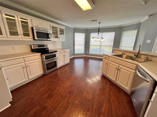 a large kitchen with cabinets wooden floor and stainless steel appliances