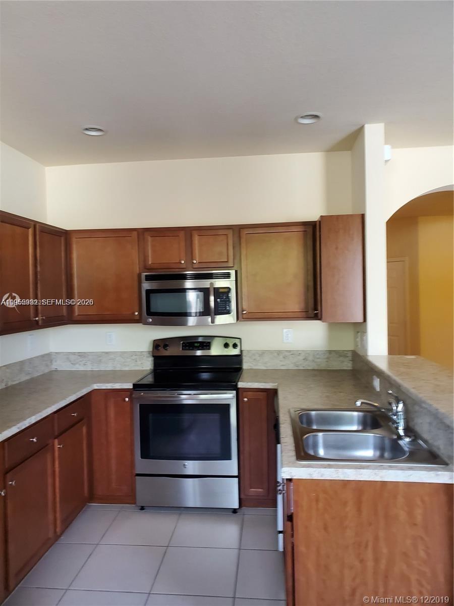 3353 West 91st Terrace Hialeah, FL 33018 - Photo 12 of 21 a kitchen with stainless steel appliances granite countertop a stove a sink and a microwave