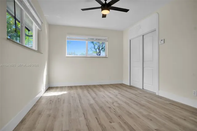an empty room with wooden floor fan and windows
