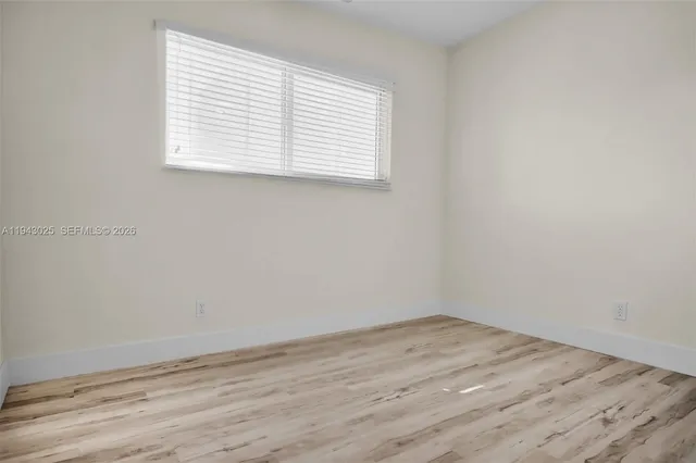an empty room with wooden floor and a window