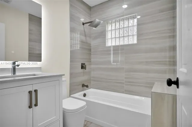 a bathroom with a granite countertop sink a toilet and shower