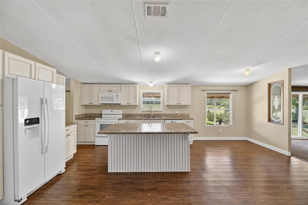 4416 Pippin Road Plant City, FL 33567 - Photo 18 of 86 a kitchen with stainless steel appliances granite countertop a refrigerator a stove oven and white cabinets with wooden floor