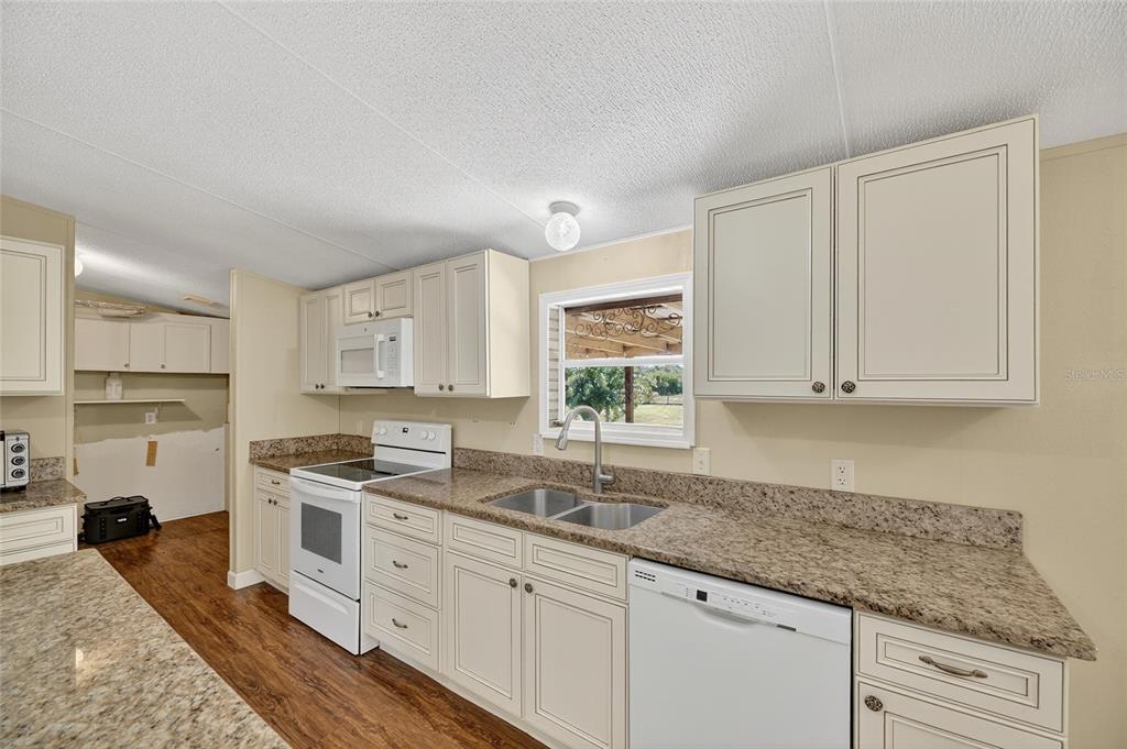 4416 Pippin Road Plant City, FL 33567 - Photo 22 of 86 a kitchen with granite countertop a sink stainless steel appliances white cabinets and a window
