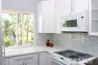 a kitchen with white cabinets and window