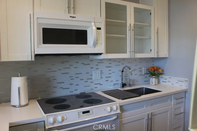 a kitchen with granite countertop white cabinets and white appliances