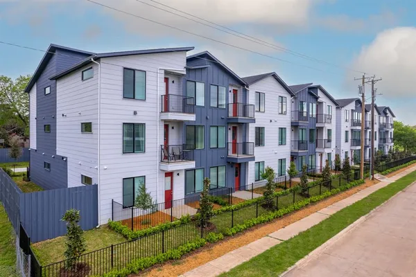 a front view of a residential apartment building with a yard and potted plants