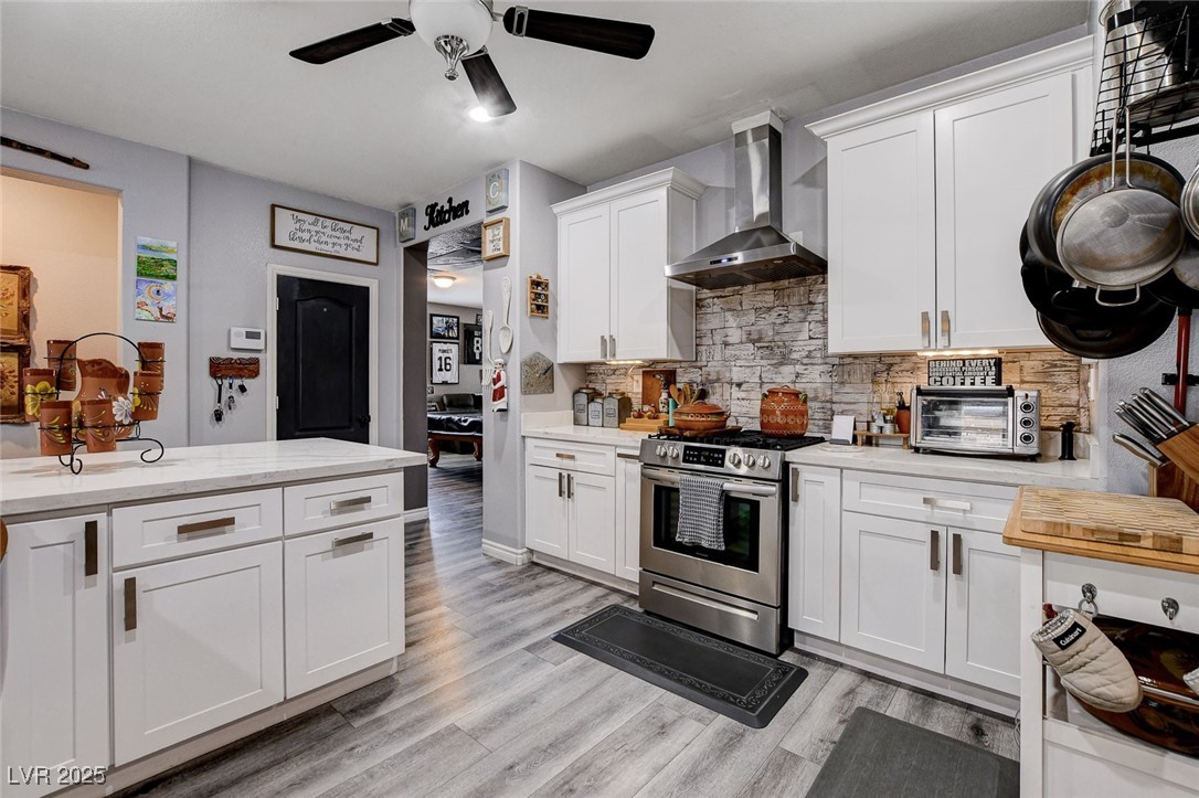5929 North Caddy Ridge Street North Las Vegas, NV 89031 - Photo 12 of 37 Kitchen with range hood, gas range, ceiling fan, white cabinets, and light wood finished floors