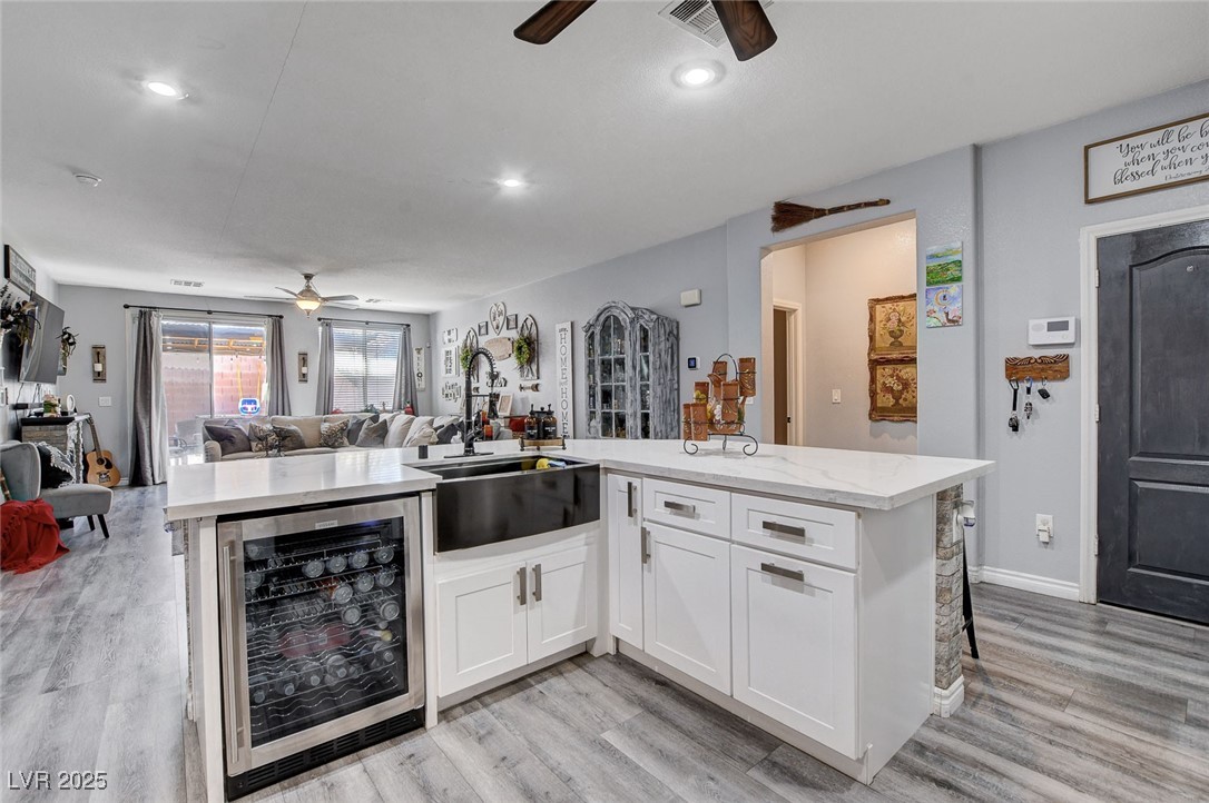 5929 North Caddy Ridge Street North Las Vegas, NV 89031 - Photo 37 of 37 Kitchen with beverage cooler, open floor plan, ceiling fan, light stone countertops, and light wood finished floors