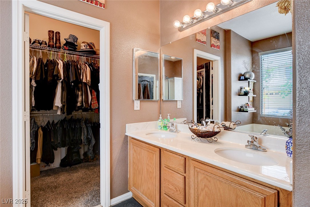 5929 North Caddy Ridge Street North Las Vegas, NV 89031 - Photo 21 of 37 Full bathroom featuring a textured wall, double vanity, a spacious closet, and a garden tub