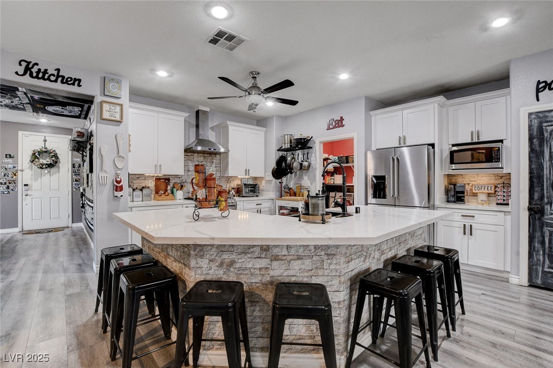 5929 North Caddy Ridge Street North Las Vegas, NV 89031 - Photo 10 of 37 Kitchen with tasteful backsplash, light wood finished floors, a spacious island, a breakfast bar, and stainless steel appliances