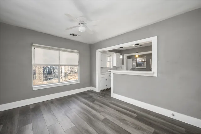 a view of an empty room with a window and wooden floor