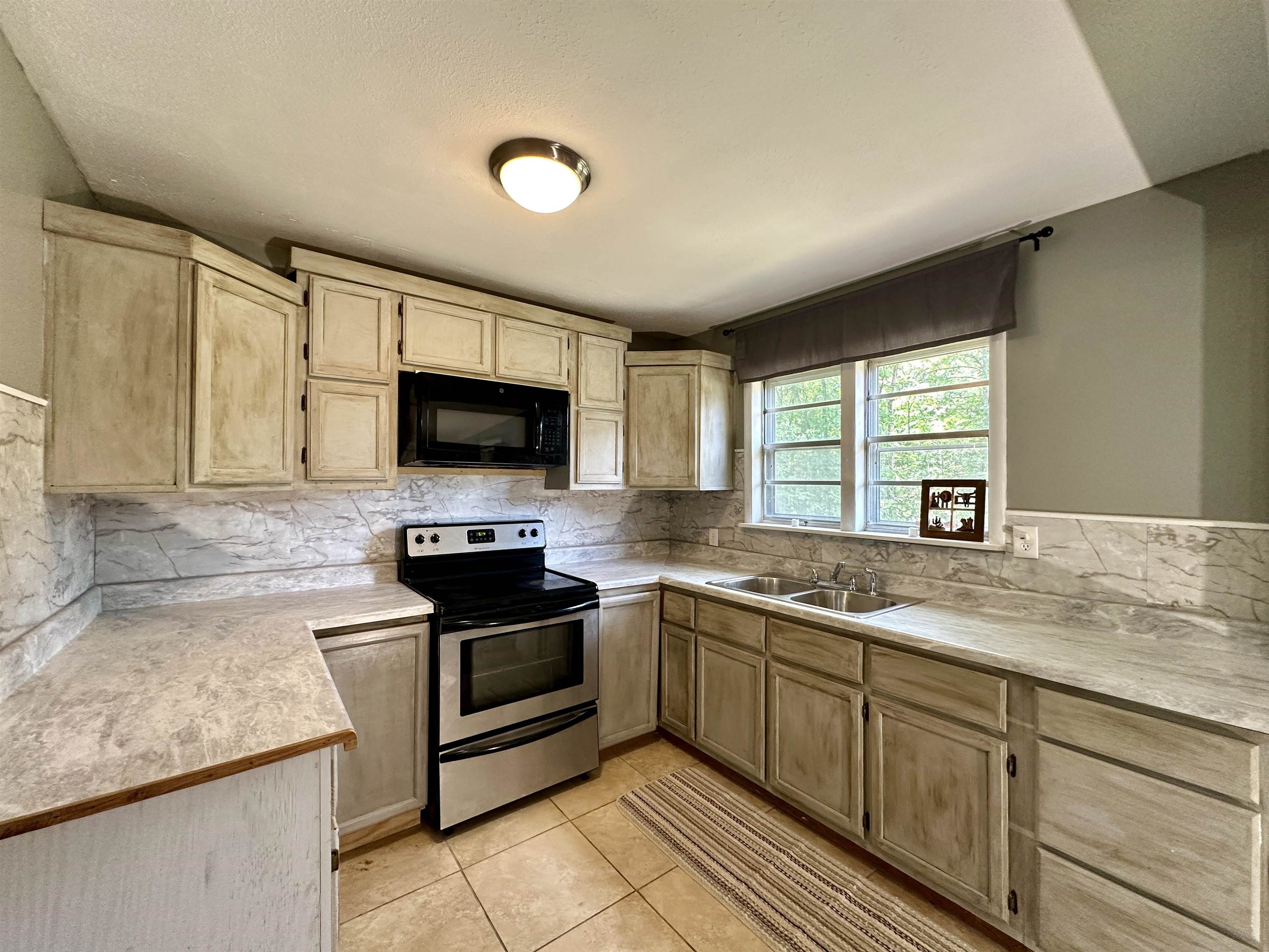 2505 Pittman Road Somerville, TN 38068 - Photo 7 of 23 Kitchen featuring light-toned cabinetry, stainless steel appliances, a double basin sink, and a tiled backsplash
