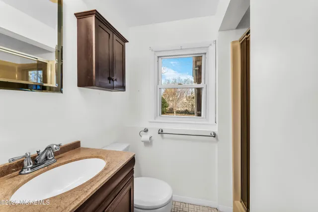 a bathroom with a granite countertop toilet sink and mirror