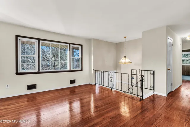a view of an empty room with window and wooden floor