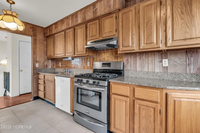 a kitchen with stainless steel appliances granite countertop a stove a sink and a refrigerator