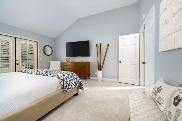 a bedroom with a bed and a flat tv screen on dresser