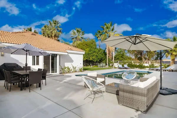 a view of a house with backyard sitting area and swimming pool