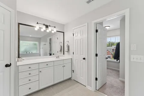 a spacious bathroom with a double vanity sink a large mirror a shower and vanity