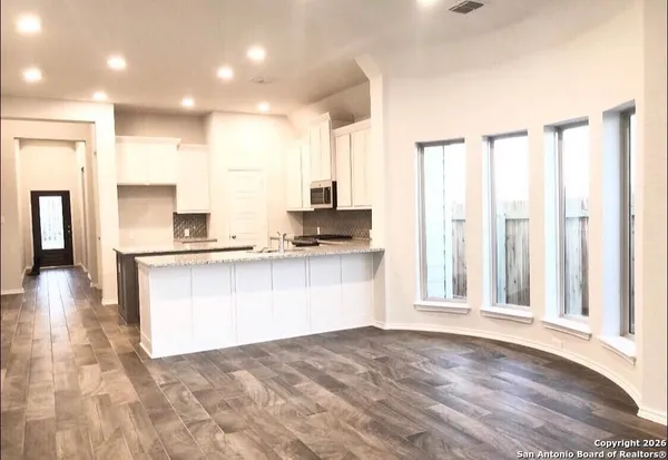 a view of a kitchen with kitchen island granite countertop a refrigerator sink and white cabinets