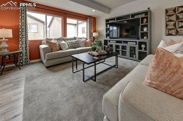 a living room with furniture a flat screen tv and a large window