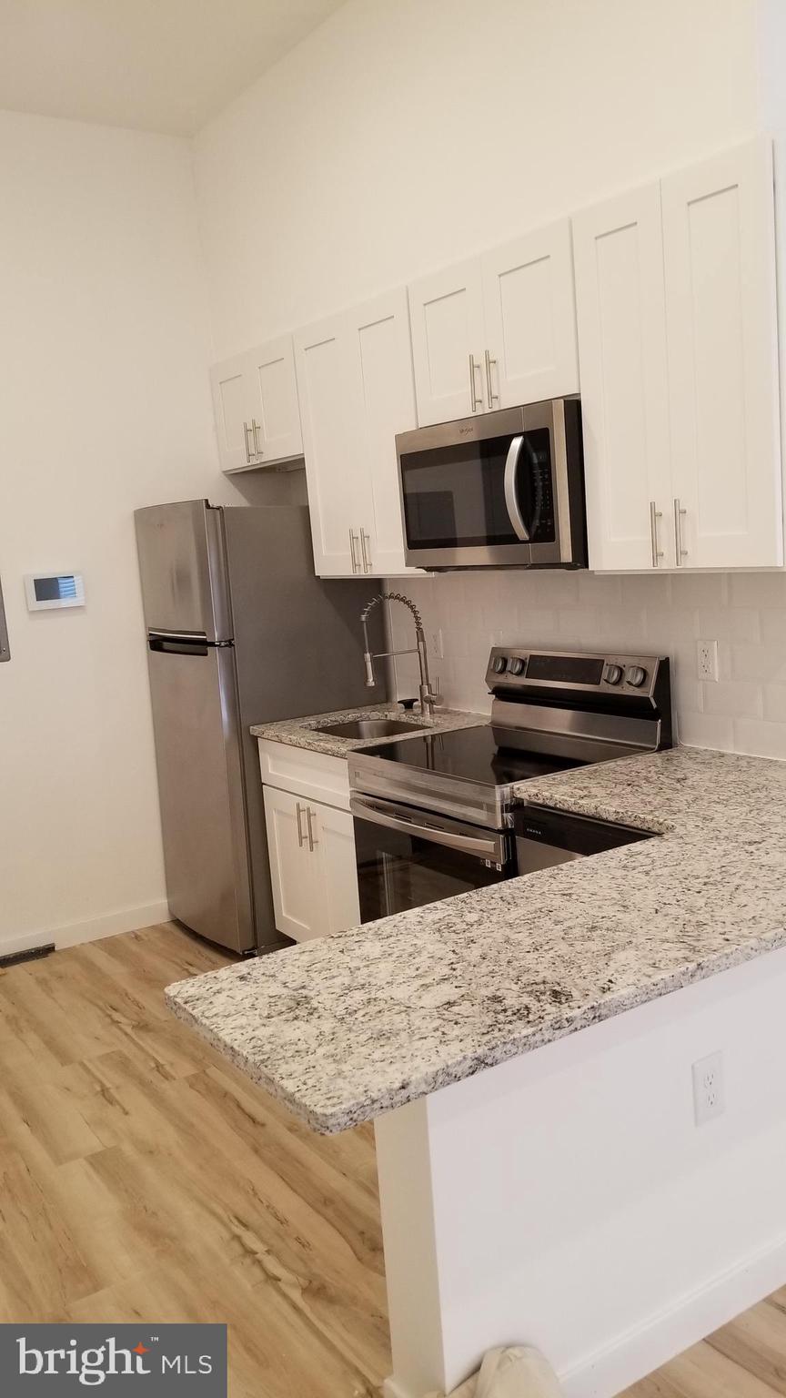 247 South 16th Street, Unit 5 Philadelphia, PA 19102 - Photo 5 of 10 a kitchen with stainless steel appliances a stove a microwave and white cabinets