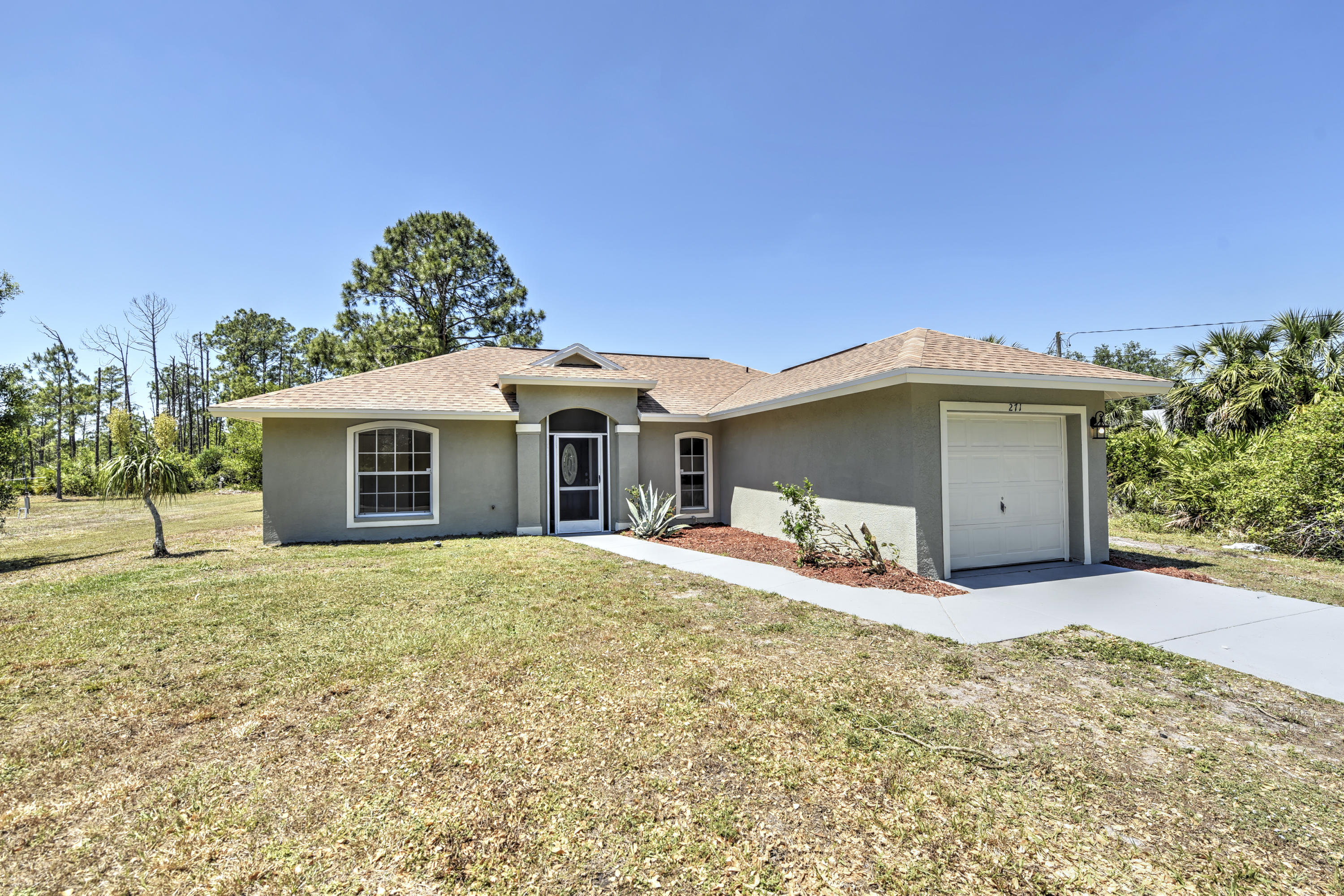 271 18th Street Southeast Naples, FL 34117 - Photo 2 of 28 a front view of a house with a yard and garage