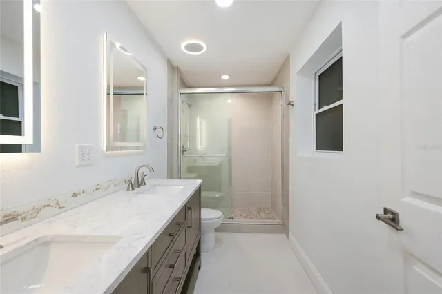 a bathroom with a double vanity sink a mirror and a shower