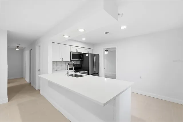 a large white room with kitchen island a sink a stove and a refrigerator
