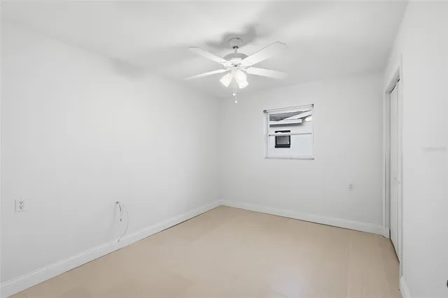 an empty room with a window and ceiling fan