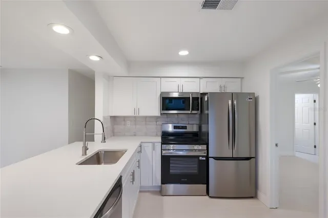 a kitchen with stainless steel appliances a refrigerator sink and microwave