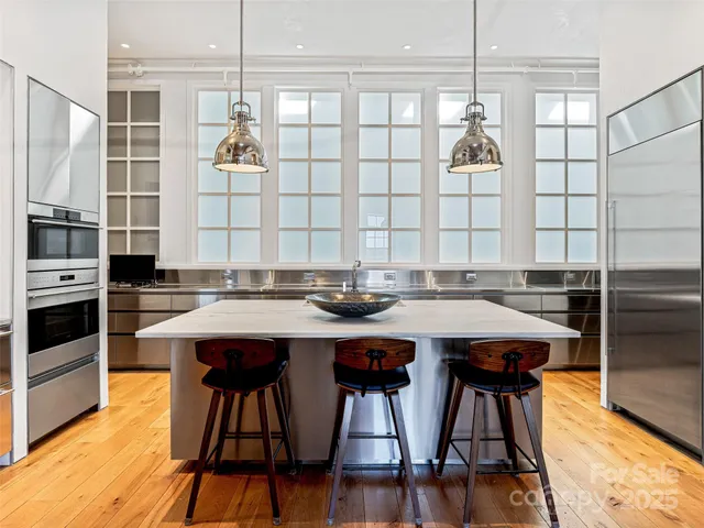a kitchen with stainless steel appliances kitchen island a table chairs in it and wooden floors