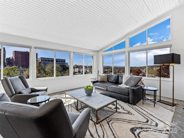 a living room with furniture kitchen view and large windows