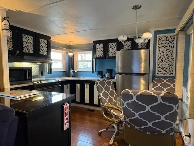 a kitchen with granite countertop a stove a refrigerator and a dining table with wooden floor