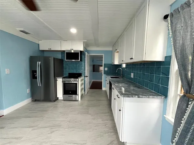 a kitchen with stainless steel appliances granite countertop a refrigerator a oven a sink with the island and wooden floor