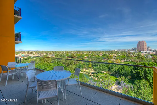 a view of a city from a balcony with dining table & chairs