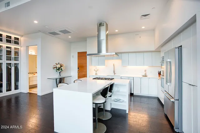 a kitchen with a sink stainless steel appliances and wooden floor
