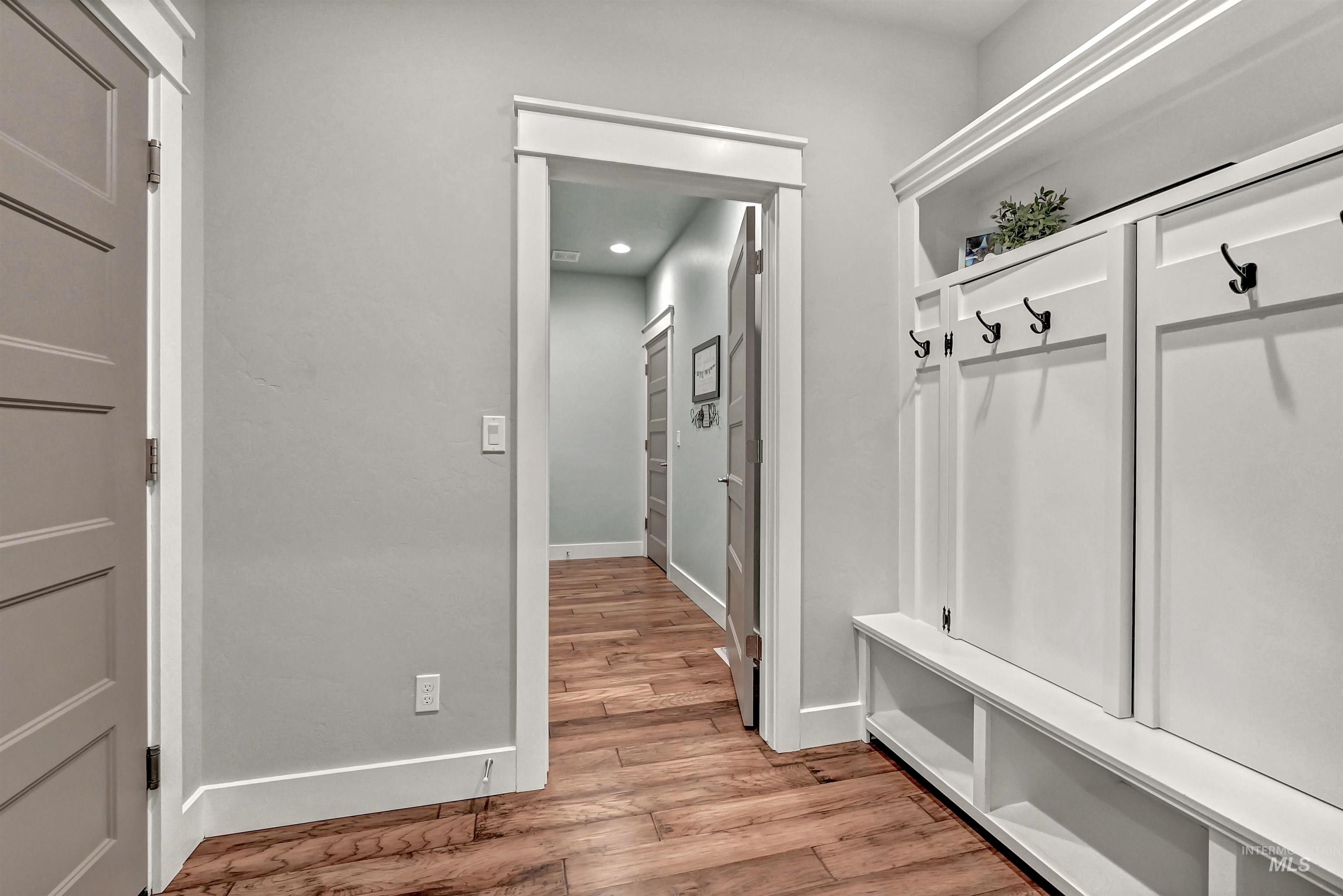 5802 South Wayland Way Meridian, ID 83642 - Photo 32 of 35 Mudroom with engineered wood flooring, a built-in white bench and doors with hooks that open to hidden shelves for tidy storage