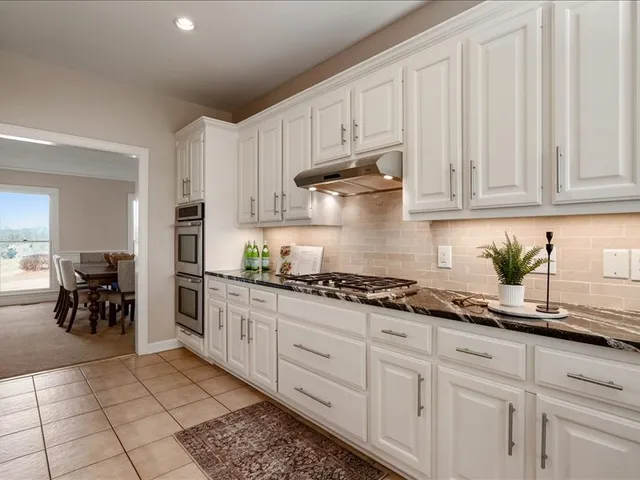 a kitchen with white cabinets and sink