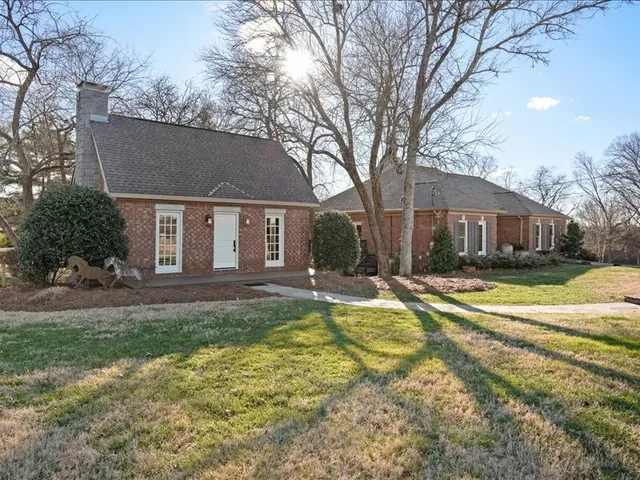 a view of house with yard and trees in the background