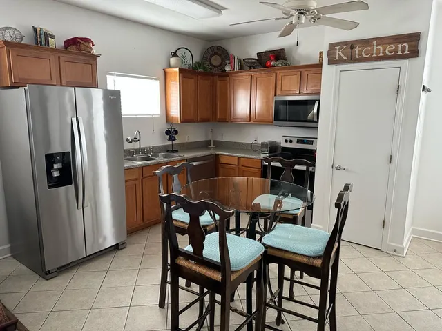 a kitchen with granite countertop a table chairs refrigerator and microwave
