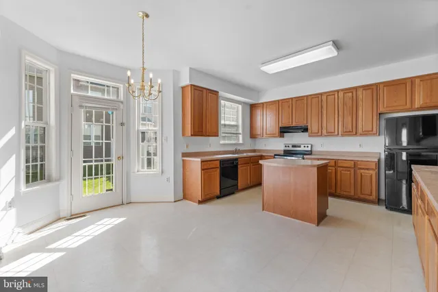 a kitchen with stainless steel appliances granite countertop a stove top oven a sink dishwasher a refrigerator and a dining table with wooden floor