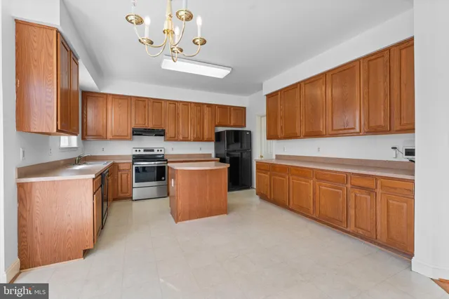 a kitchen with stainless steel appliances granite countertop a stove top oven a sink dishwasher and a refrigerator with wooden cabinets