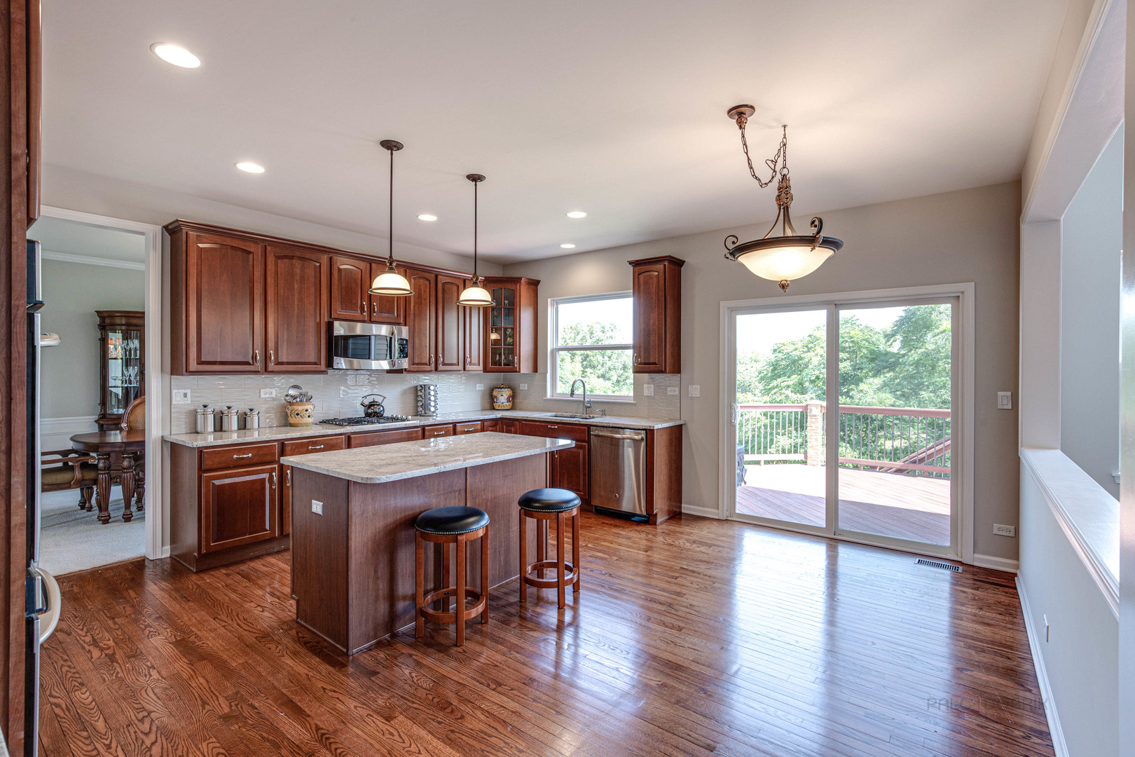 409 Wildflower Way Streamwood, IL 60107 - Photo 11 of 53 wooden kitchen with stainless steel appliances granite countertop wooden floors wooden cabinets a center island and a window