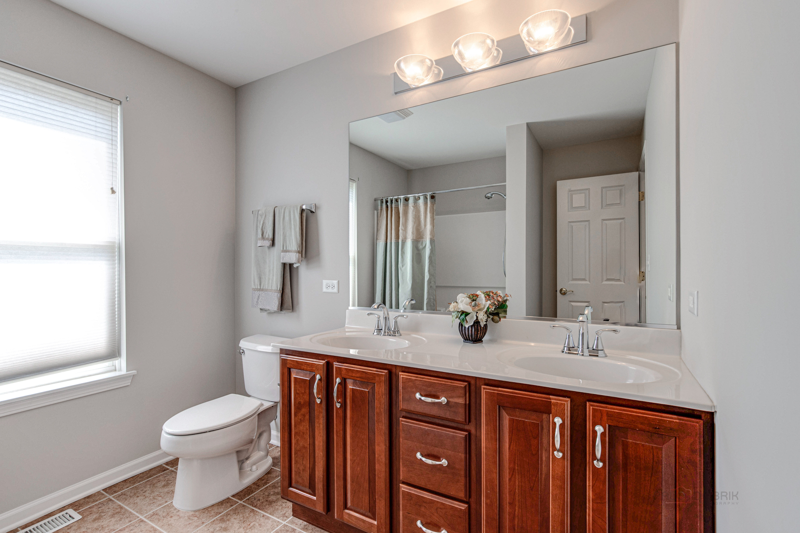 409 Wildflower Way Streamwood, IL 60107 - Photo 27 of 53 a bathroom with a granite countertop toilet a sink a large mirror and a window