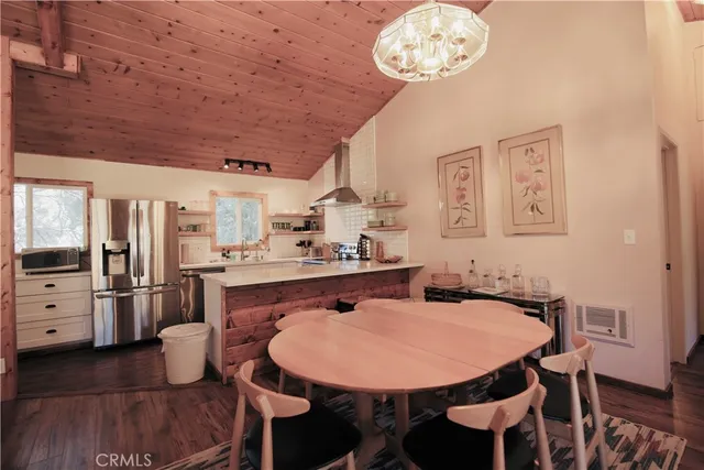 a kitchen with stainless steel appliances kitchen island granite countertop a table chairs and a refrigerator