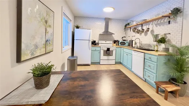 a kitchen with stainless steel appliances kitchen island granite countertop a refrigerator a stove top oven and a potted plant