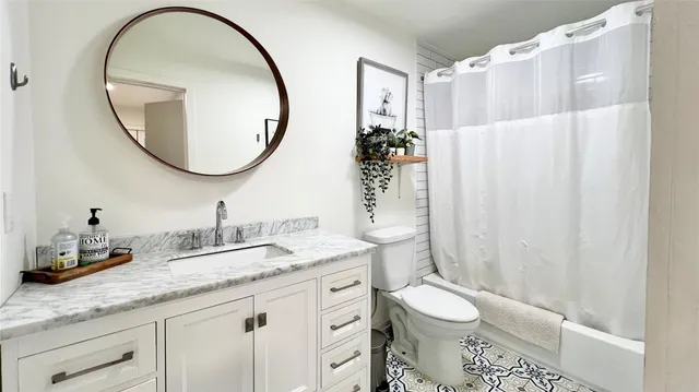 a bathroom with a granite countertop sink mirror vanity and toilet