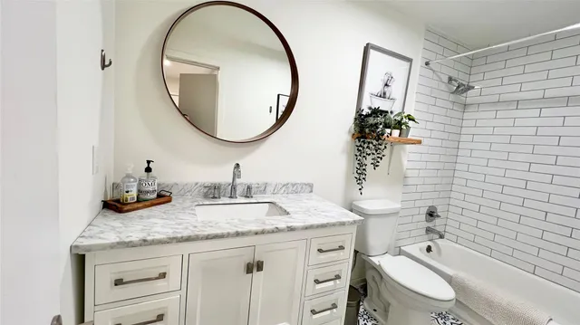 a bathroom with a granite countertop toilet a sink and a mirror